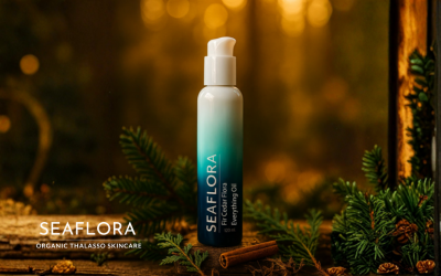 Seaflora's Fir Cedar Flora Everything Oil bottle sits on moss in a lush Pacific Northwest forest. It's surrounded by fir and cedar sprigs, and cinnamon, with the white Seaflora logo in the bottom left corner.